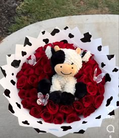 a teddy bear sitting on top of a bouquet of roses in the shape of a heart