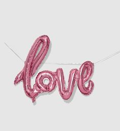 the word love spelled out in pink foil balloons on a string with two strings attached to it