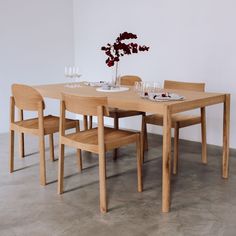 a wooden table with four chairs and a vase filled with flowers on top of it