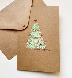 two brown envelopes with christmas trees on them, one is open and the other has a red heart