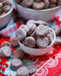 two bowls filled with chocolate covered donuts on top of a red and white table cloth