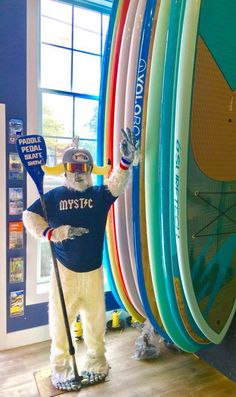 a man dressed as a polar bear standing in front of surfboards and holding a paddle