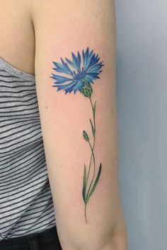 a woman's arm with a blue flower tattoo on the left side of her arm