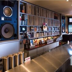 a room with many bookshelves and speakers on the wall, along with stainless steel counter tops