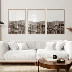 a living room with white couches and two paintings on the wall above them, along with a coffee table