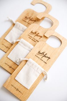 three wooden bottle openers with white linen bags tied around the top one is open and two are closed