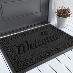 a welcome mat with the word welcome on it next to a potted plant and door