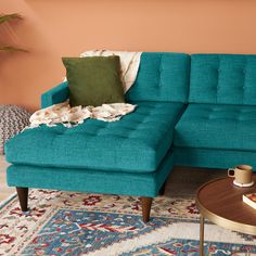 a living room with a couch, coffee table and rugs on the floor in front of an orange wall