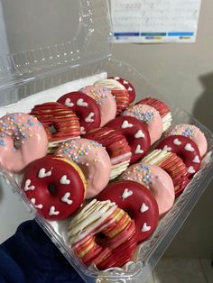 red and white donuts with sprinkles in a plastic container