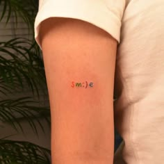 a person with a small tattoo on their arm that says,'smile'in multicolored letters