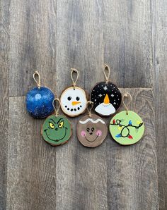 six christmas ornaments are hanging on a wooden floor, one has an ornament in the shape of a snowman