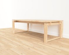 a wooden table sitting on top of a hard wood floor next to a white wall