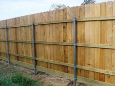 a wooden fence with metal piping on the top and bottom bars attached to it