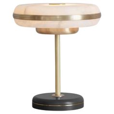 a table lamp with a white shade on it's top and gold trim around the base