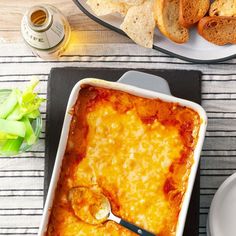 a casserole dish with cheese and bread on the side