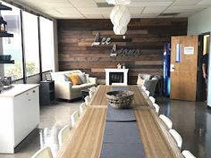 a long wooden table sitting in the middle of a room with white chairs and tables