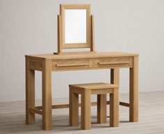 a wooden dressing table and stool with a mirror on the top, against a white wall