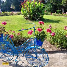 a blue bicycle is sitting in the middle of a flower garden with pink flowers on it