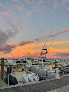 several boats docked at a pier with the sun setting in the sky behind them,