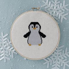 a cross - stitch penguin is shown in front of snowflakes