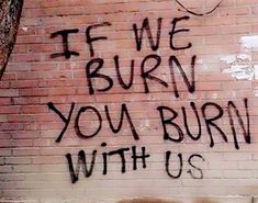 graffiti on the side of a brick building reads, if we burn you burn with us