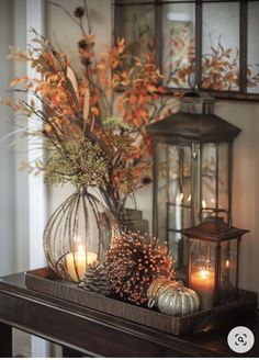 candles are lit on a mantle with autumn decorations