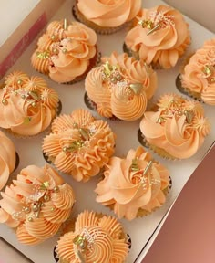 a box filled with cupcakes covered in orange frosting and topped with flowers