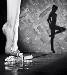 a person standing in front of a wall with their shadow on the floor and shoes