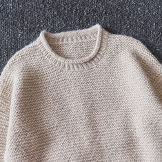 a white sweater sitting on top of a gray carpet