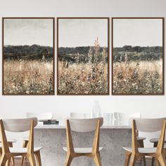 three paintings hanging on the wall above a dining room table with four chairs in front of it