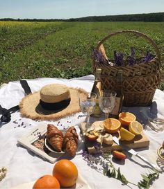 a picnic table with bread, oranges and wine on it in the middle of an open field