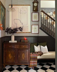 a living room with black and white checkered flooring next to a stair case