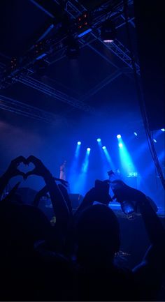 the stage is lit up with bright blue lights and hands in the shape of a heart