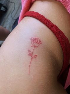 a small rose tattoo on the back of a woman's thigh