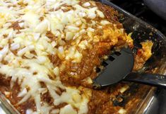 a casserole dish with cheese and onions in it, being held by a spatula