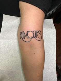 a man with a tattoo on his arm that says rumours in cursive writing