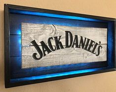 a wooden sign that reads jack daniels on it's side with blue light underneath