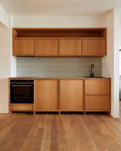 an empty kitchen with wooden cabinets and wood floors