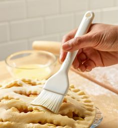 a person using a brush to clean a pie crust