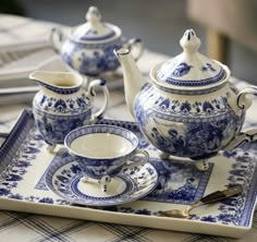 a blue and white tea set on a tray with utensils next to it