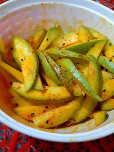 a white bowl filled with green beans and seasoning on top of a red table