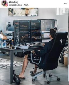 a man sitting at a desk in front of two computer monitors with graphs on them