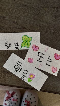 three children's shoes are sitting on the floor next to two cards with words written in korean and english