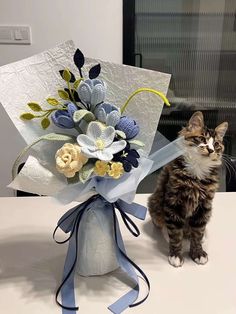 a cat sitting next to a bouquet of flowers