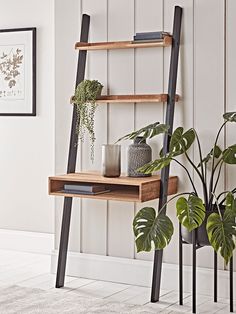 a wooden shelf with plants and books on it next to a potted houseplant