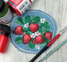 the strawberries and daisies are on the blue placemat next to paintbrushes