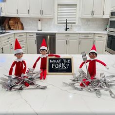 three elfs sitting on top of a kitchen counter with forks and spoons in front of them