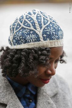 a woman wearing a blue and white knitted hat with trees on the side,