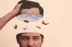 a man is holding his head with butterflies on it's forehead and the image of a sky above him