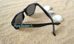 a pair of black sunglasses sitting on top of a sandy beach next to white rocks